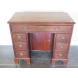 A mahogany seven drawer kneehole desk with central cupboard, 79cm tall x 90cm x 45cm