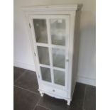 A white painted glazed cabinet with a drawer, 121cm taqll x 49cm x 33cm