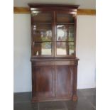 A 19th century flame mahogany cupboard bookcase with two glazed doors over a drawer and two cupboard