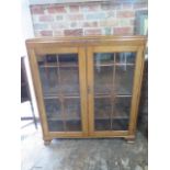A light oak two door display cabinet with adjustable shelving, 122cm tall x 107cm x 29cm, in good