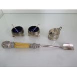 A pair of silver salts with silver spoons, a silver mustard and a plated cheese scoop with silver