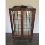 A walnut two door glazed display cabinet on ball and claw feet, 126cm tall x 75cm x 36cm