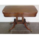 A 19th century rosewood fold over card table on twin turned columns and quatrefoil base
