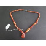 A carnelian bead necklace with axe head shaped centre, 54cm long, beads range from 10 to 4mm,