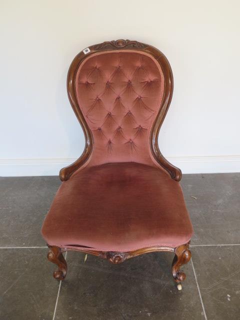 A Victorian carved walnut button back fireside chair