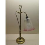 A brass adjustable desk lamp with a cranberry tinted shade, in generally good condition, working