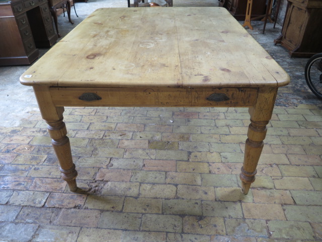 A Victorian stripped pine table with two end drawers and a side drawer on turned legs, 77cm tall x