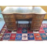 A mahogany serpentine fronted nine drawer kneehole desk with a leather inset top, 75cm tall x