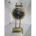 A brass twin pillar drum gravity clock, 26cm tall, ticks but stops