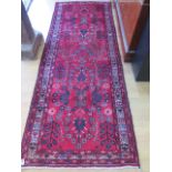 A rich red ground hand woven woollen runner with unique all over design in good condition, 270cm x