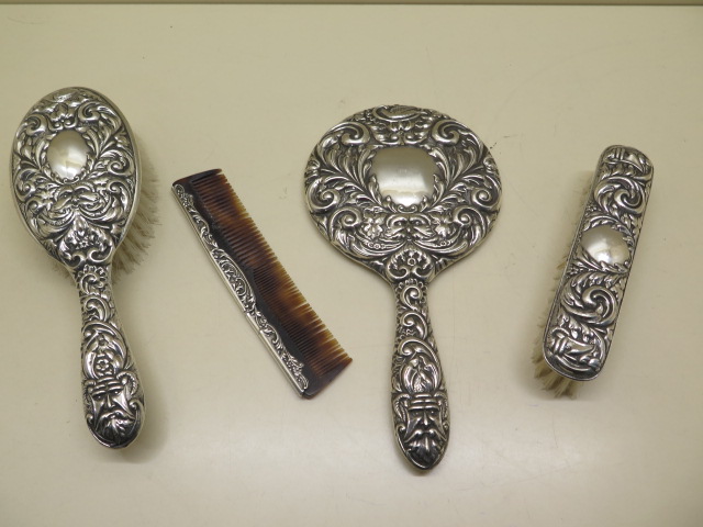 A silver embossed dressing table set, some wear and bending to comb but reasonably good