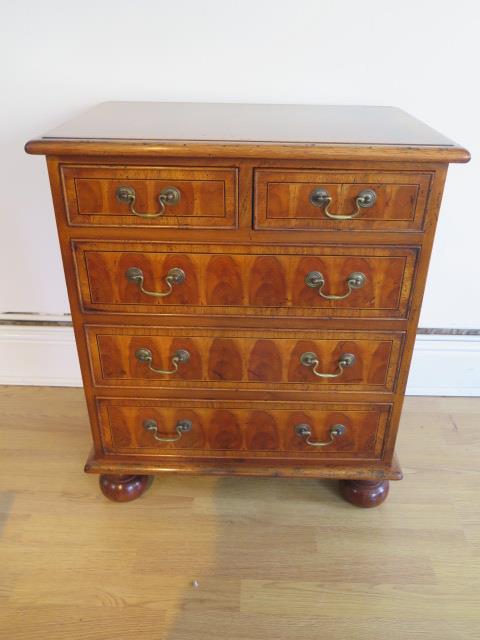 A yew oyster veneer chest of small proportions with two short over three long drawers on turned feet