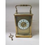 A brass carriage clock striking on a gong, 18cm tall with handle up, running order, one glass
