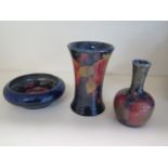 Three pieces of blue ground Moorcroft, a pin dish, beaker vase 11cm tall, and a small bottle vase,