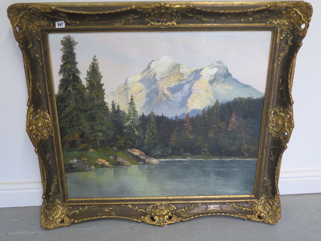 An oil on canvas Swiss Alpine scene with lake to foreground, indistinctly signed, in a gilt swept