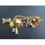 A 9ct yellow gold charm bracelet with 14 charms, most marked for 9ct, and a hallmarked 18ct ring,