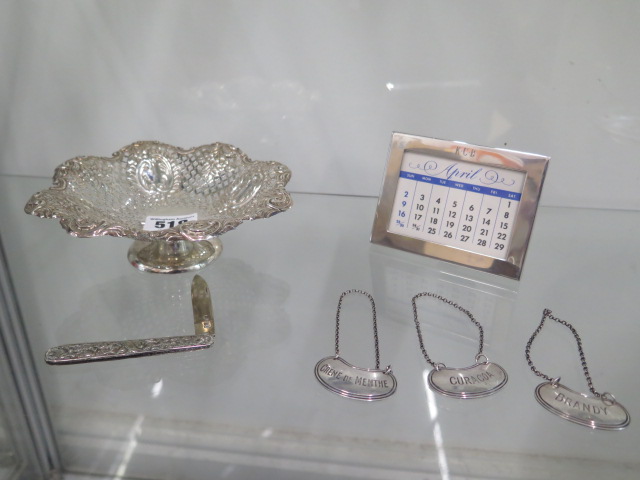 A silver sweetmeat dish, a silver Tiffany calendar, three silver spirit labels and a silver fruit
