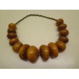 A string of large pebble shaped butterscotch amber beads, largest 6cm x 6cm x 3cm, smallest 3.5cm