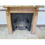 A decorative 19th century cast iron fireplace with a pine surround, size 120cm tall x 143cm wide,