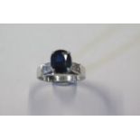 An 18ct white gold solitaire sapphire ring size N, sapphire approx 8mm x 7mm x 3mm, flanked either