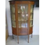 An Edwardian mahogany display cabinet with an astragel glazed door and bow glass sides standing on