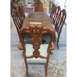 A shaped walnut dining table with a carved frieze on carved cabriole legs having 8 matching dining