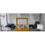 A show case with 10 modern quartz watches, 7 other watches and some boxes, some appear unworn
