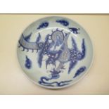 A Chinese Qing Dynasty porcelain dish decorated with a dragon chasing a pearl with a cloud surround,