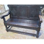 An 18th / 19th century carved oak settle with scroll arms on turned supports, 100cm tall x 137cm x