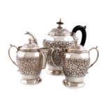 A three-piece Indian metalware tea set, unmarked hinged covers, baluster form, chased foliate scroll