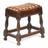 A QUEEN ANNE OAK JOINT STOOL C.1705 with a later needlework drop-in seat, on ring turned baluster