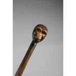 A CARVED WOOD WALKING CANE C.1920 the handle decorated with a double monkey head, with glass eyes,