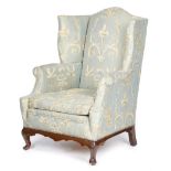 A WING ARMCHAIR IN GEORGE II STYLE FIRST HALF 20TH CENTURY with scroll arms and shell capped