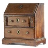 AN OAK MINIATURE BUREAU 18TH CENTURY with a hinged fall revealing three pigeonholes, above two