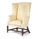 A GEORGE III MAHOGANY WING ARMCHAIR C.1780-90 upholstered with damask fabric, with scroll arms, on
