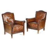 A PAIR OF BROWN LEATHER EASY ARMCHAIRS FIRST HALF 20TH CENTURY each with an arched back and scroll