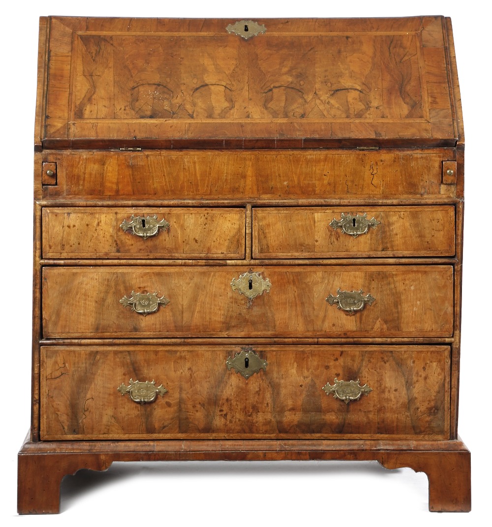 A GEORGE I WALNUT BUREAU C.1715 with cross and feather banding, the hinged fall revealing an