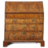 A GEORGE I WALNUT BUREAU C.1715 with cross and feather banding, the hinged fall revealing an