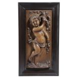 AN ITALIAN CARVED WALNUT CHERUB PANEL FLORENCE, C.1880 depicting a Bacchanalian putto holding a