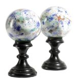 A PAIR OF GLASS SPHERES EARLY TO MID-20TH CENTURY each with splash painted interiors, on a turned