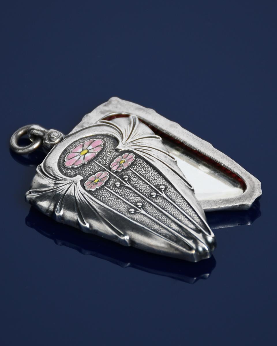 A Jugendstil Firma Erhard and Sohne silver and enamel locket, cast in low relief with Art Nouveau