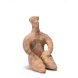 A Tel Halaf terracotta male idol circa 4th Millennium BC seated, wearing a headdress with painted