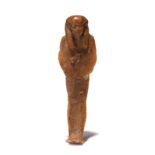 An Egyptian wax shabti wearing a tripartite wig and with remains of red wax decoration to the