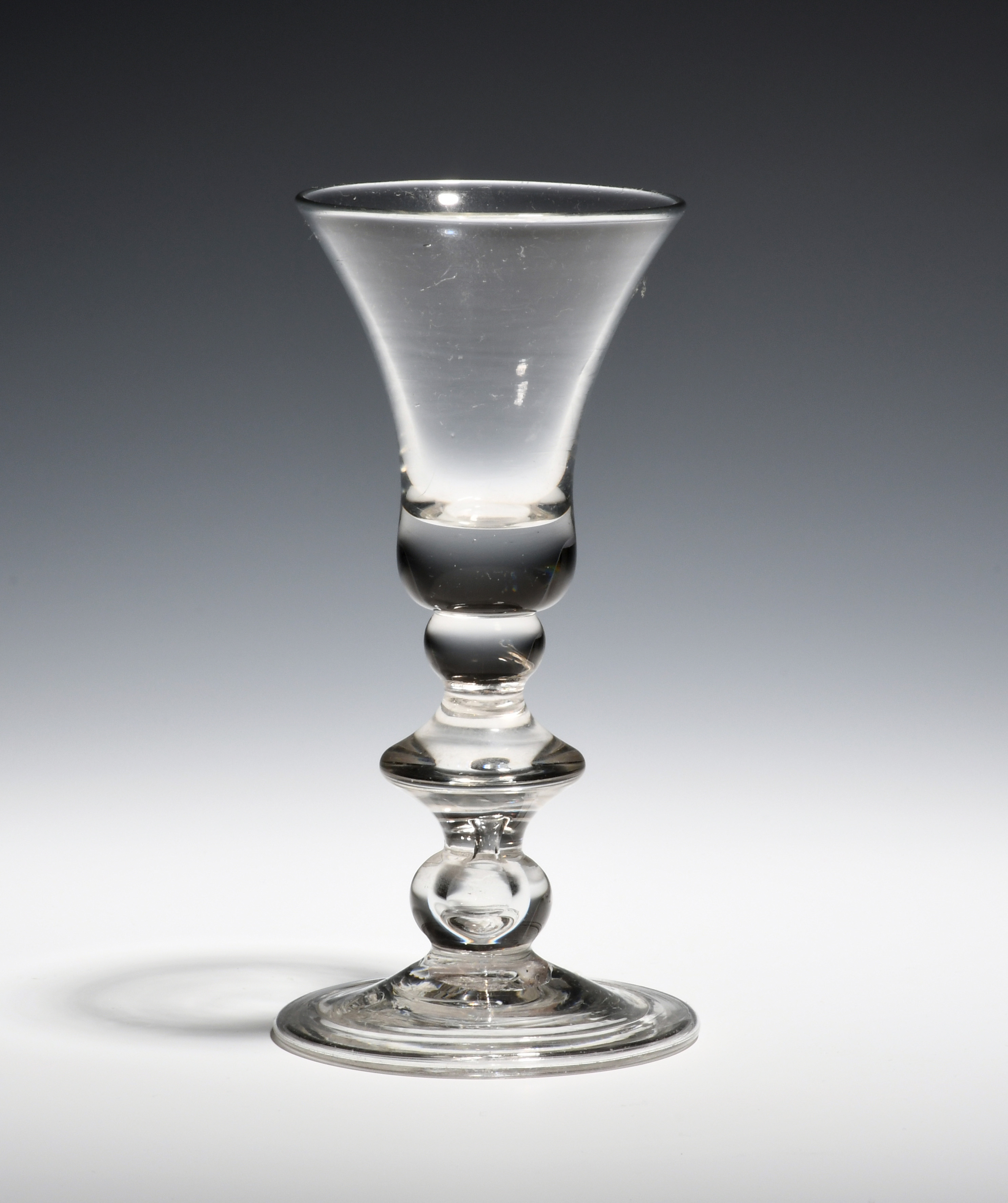 A baluster glass c.1720, with bell bowl raised on a baluster stem comprising a short knop above a