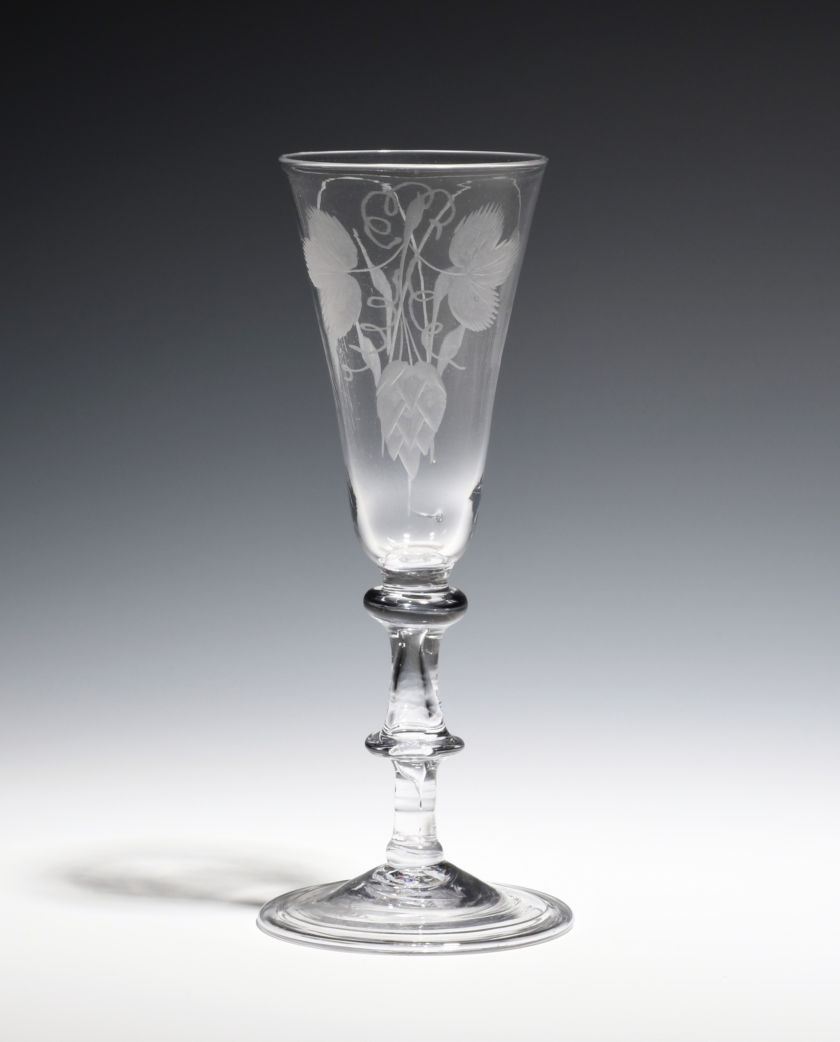 A balustroid ale glass c.1750, the round funnel bowl engraved with hops and barley above a triple-