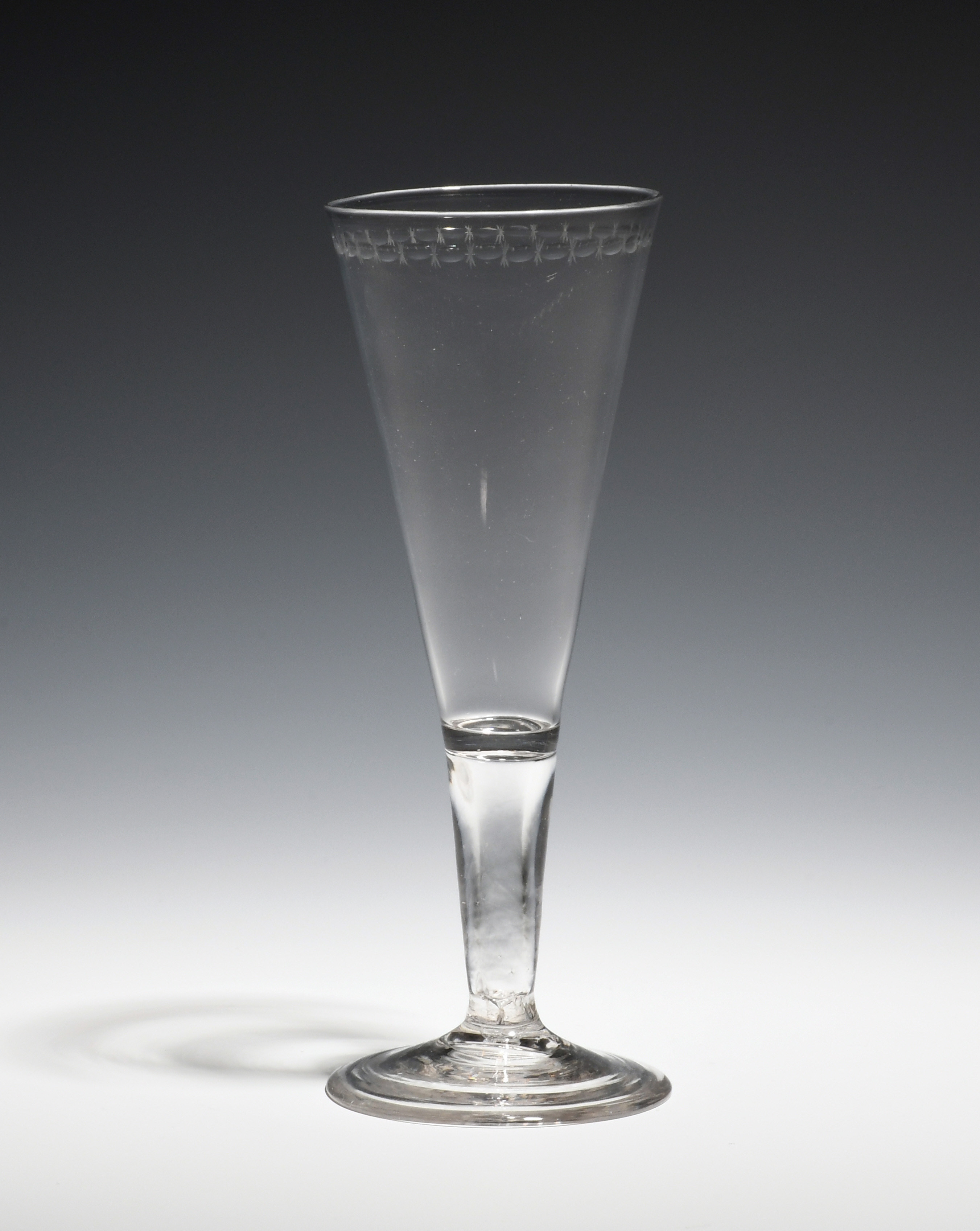 An ale glass c.1770, the drawn trumpet bowl engraved with an 'OXO' border, raised on a plain