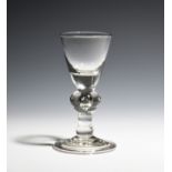 A baluster wine glass c.1715, the short round funnel bowl raised on a baluster stem with cushion