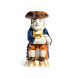 A Pratt ware toby jug c.1790-1800, of Ordinary type, seated with a foaming jug of ale resting on one