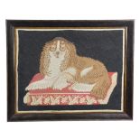 AN EARLY VICTORIAN FOLK ART NAIVE WOOLWORK OF A DOG C.1840-50 the spaniel lying on a cushion, in a