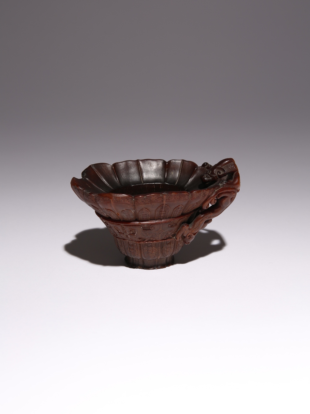 λ A CHINESE ARCHAISTIC RHINOCEROS HORN 'CHILONG' LIBATION CUP 17TH/18TH CENTURY Carved to the